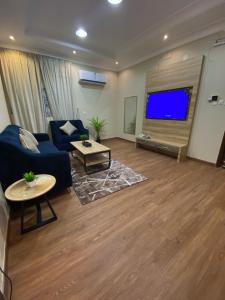a living room with a blue couch and a flat screen tv at الاطلاله للشقق المخدومة in Khamis Mushayt