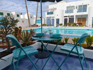 a patio with a table and chairs next to a swimming pool at BLU in Puerto del Carmen