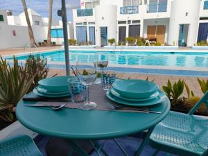 a table with plates and wine glasses next to a swimming pool at BLU in Puerto del Carmen