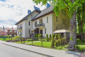 une grande maison avec une clôture devant elle dans l'établissement Medziotoju Apartment in Old City, à Palanga