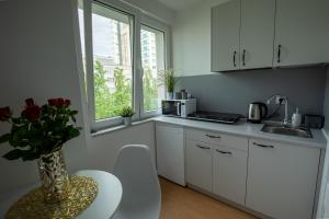 a kitchen with white cabinets and a table and a window at Apartament Ola in Warsaw
