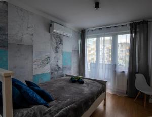een slaapkamer met een bed met blauwe kussens en een raam bij Apartament Ola in Warschau