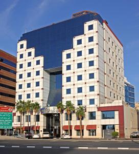 a large white building with palm trees in front of it at Sea View Hotel Dubai in Dubai