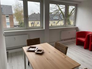 a room with a wooden table and chairs and windows at interaktiv Appartements in Ratingen - Düsseldorferstrasse in Ratingen