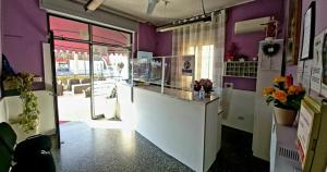 a restaurant with purple walls and a counter with flowers at Hotel Violetta in Parma