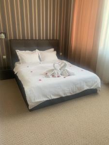 uma cama com lençóis brancos e um laço em GIA Suites em Caracal