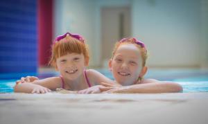 
two little girls sitting on the floor in a swimming pool at Clayton Hotel Cork City in Cork
