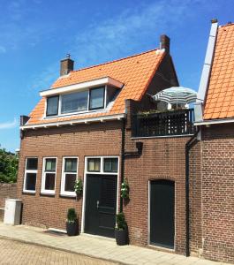 a brick house with an orange roof and a balcony at Vakantiehuis De Oude Bakkerij in Katwijk aan Zee