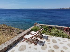 two chairs sitting on a patio near the water at Ithaca in Perdika