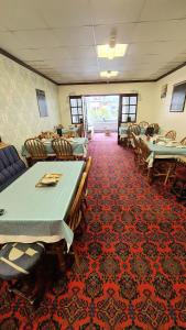 un comedor con mesas y sillas sobre una alfombra roja en The Beverley Hotel, en Blackpool