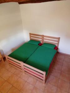 - un lit en bois avec des draps verts dans l'établissement Agri Scinghiöra, à Brontallo