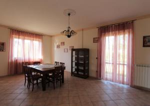 ein Esszimmer mit einem Tisch, Stühlen und Fenstern in der Unterkunft Villa Green - Irpinia in Venticano