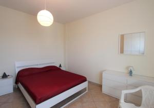 a white bedroom with a red bed and a chair at Villa Green - Irpinia in Venticano