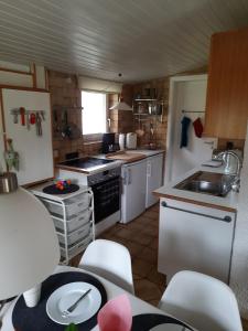 eine Küche mit weißen Geräten sowie einem Tisch und Stühlen in der Unterkunft Ferienhaus Schmidt in Bernau am Chiemsee