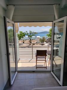 a balcony with a chair and a view of the ocean at Sea View Apartments Nikos in Nea Peramos