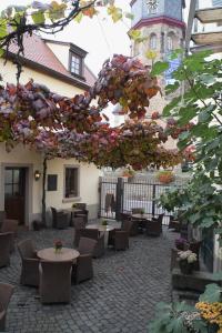 a courtyard with tables and chairs and a building with a clock tower at Hotel Kallstadter Hof in Kallstadt