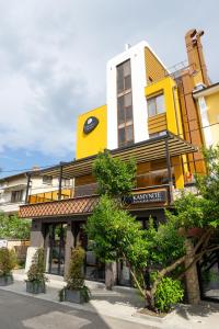 a yellow and white building with a clock on it at Хотел Камъните in Burgas City