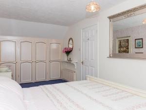 a white bedroom with a bed and a mirror at Holiday Home Ducks Dive by Interhome in Saint Keyne