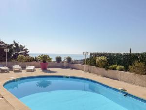a swimming pool in a yard with two lounge chairs at Apartment Princesse by Interhome in Les Issambres