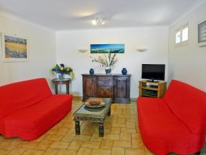 a living room with two red chairs and a tv at Apartment Princesse by Interhome in Les Issambres +25 photos