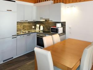 una cucina con tavolo in legno e armadietti bianchi di Apartment Pinsons by Interhome a Thyon-Les Collons