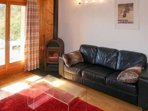 - un canapé en cuir noir dans le salon avec cheminée dans l'établissement Apartment Pinsons by Interhome, à Les Collons