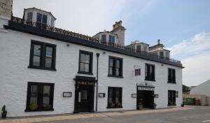 a white building with black windows on a street at The Crown Hotel in Newton Stewart