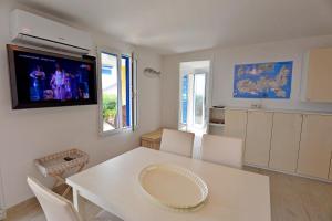 a kitchen with a white table and a tv on the wall at La Perla del Golfo in Capoliveri