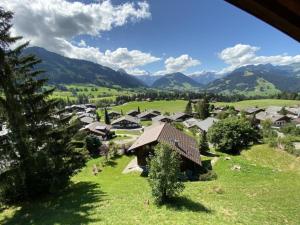 a village in a green field with mountains in the background at Apartment Sonnige Matte by Interhome in Gstaad