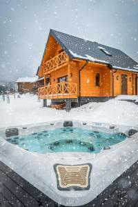 a log cabin in the snow with a hot tub at Miodówka - komfortowy dom w górach in Glinka