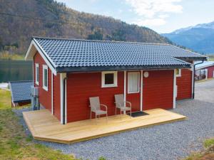 a red tiny house with two chairs on a deck at Holiday Home Raumelen - FJS018 by Interhome in Balestrand