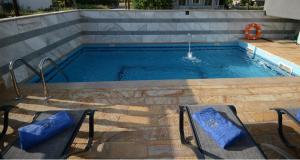 a swimming pool with two chairs and a fountain at NABRO Resort in Paralia Katerinis