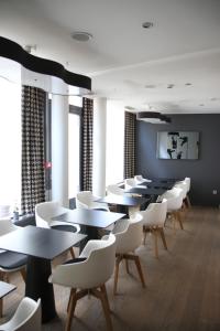 a dining room with tables and white chairs at Hôtel Quatorze in Colmar