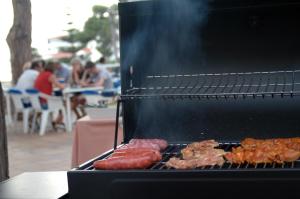 una parrilla con salchichas y otros alimentos. en GHT Xaloc, en Platja d'Aro