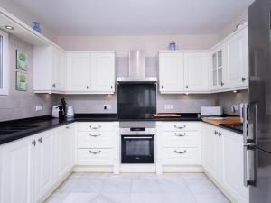 uma cozinha com armários brancos e electrodomésticos pretos em Holiday Home Cielo Azul by Interhome em Benitachell