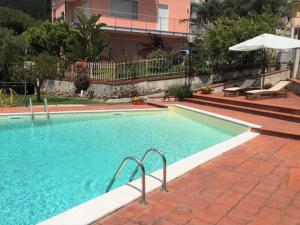 ein großer Pool mit Sonnenschirm neben einem Gebäude in der Unterkunft Holiday Home Dada by Interhome in Boissano