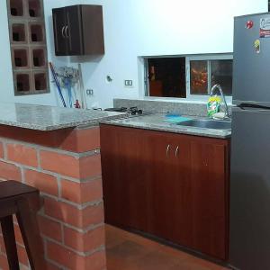 a kitchen with a counter and a refrigerator and a sink at Apartasol El Encanto in San Jerónimo