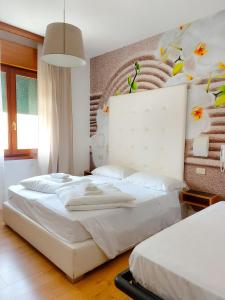 un dormitorio con 2 camas y una pared con flores. en Hotel Regina, en Caorle
