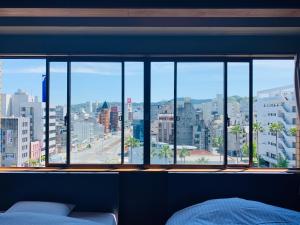 een slaapkamer met een groot raam met uitzicht op de stad bij Hotel Takasago in Kochi
