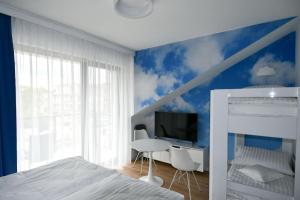 a bedroom with a white bed and a blue wall at Blue Sky Apartments Rezydencja Niechorze - 302 in Niechorze