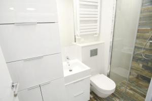 a white bathroom with a toilet and a sink at Blue Sky Apartments Rezydencja Niechorze - 302 in Niechorze