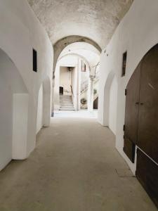 un couloir vide dans un vieux bâtiment avec des murs et des plafonds blancs dans l'établissement mille e una notte, à Bergame