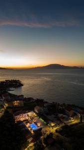 Blick auf eine Stadt mit Meer bei Sonnenuntergang in der Unterkunft Villa Corali Apartments Sea Breath & Pool in Ammoudi