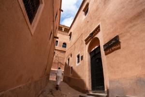 Um homem a andar por um beco entre dois edifícios. em Dar Kamar em Ouarzazate