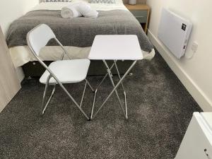 two white chairs and a table in front of a bed at 2B SPV Double En-suite Room in Wakefield