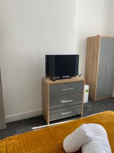 um quarto com uma televisão numa cómoda com uma cama em 2C SPV Double En-suite Room em Wakefield