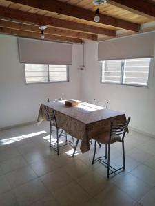 a table and chairs in a room with two windows at Duplex Chacabuco in San Fernando del Valle de Catamarca