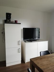 a living room with a television on a white cabinet at Ferienhof Gassner in Mondsee
