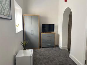 a room with a tv and a dresser with a television at 2D SPV Double En-suite Room in Wakefield