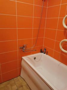 ein orangefarbenes gefliestes Bad mit einer Badewanne in der Unterkunft Laisvės 10 in Telšiai